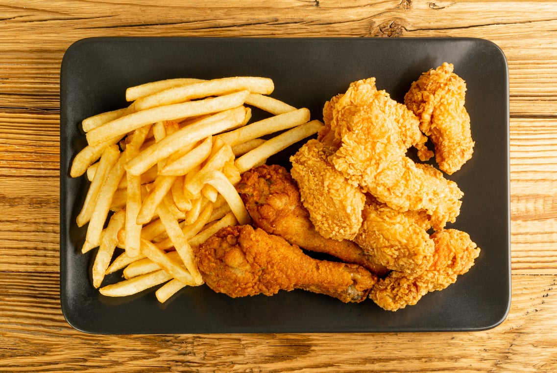 Breaded Fried Chicken Wings, Fingers and Drumsticks on Wooden Ru